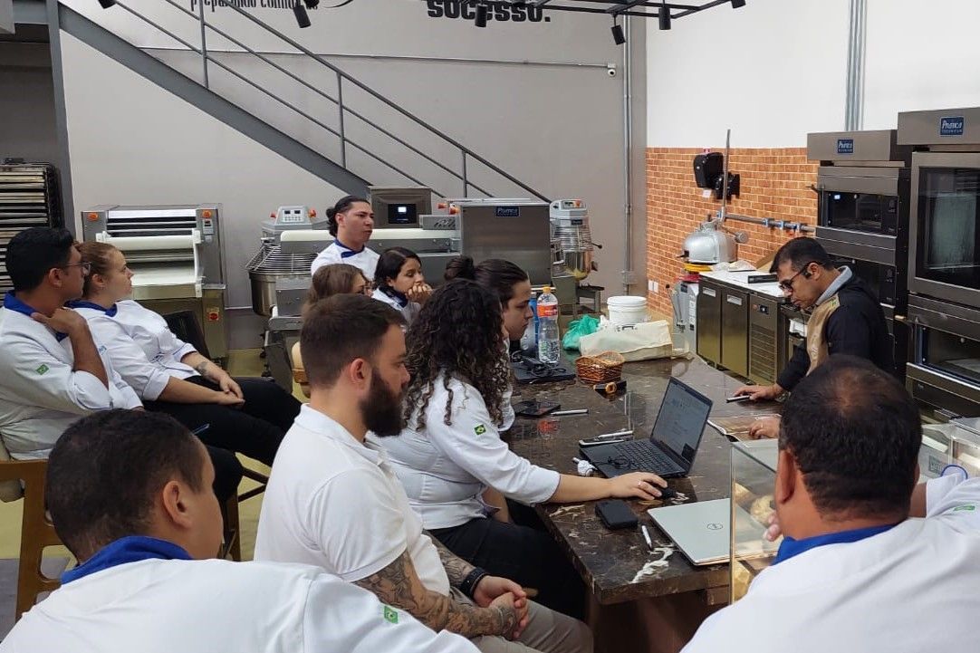 Um grupo de pessoas está sentado ao redor de uma mesa na cozinha.