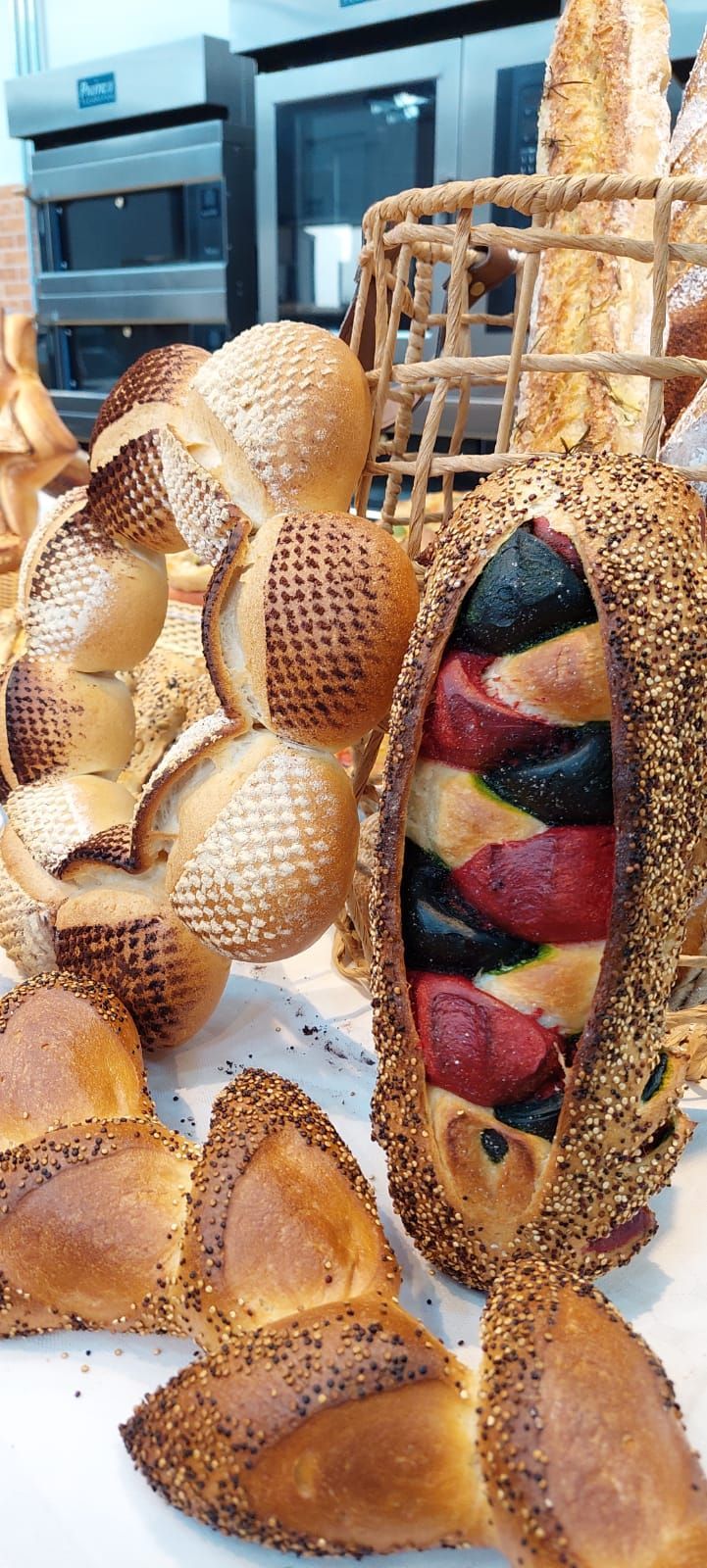 Um monte de pães estão sobre uma mesa em uma padaria.