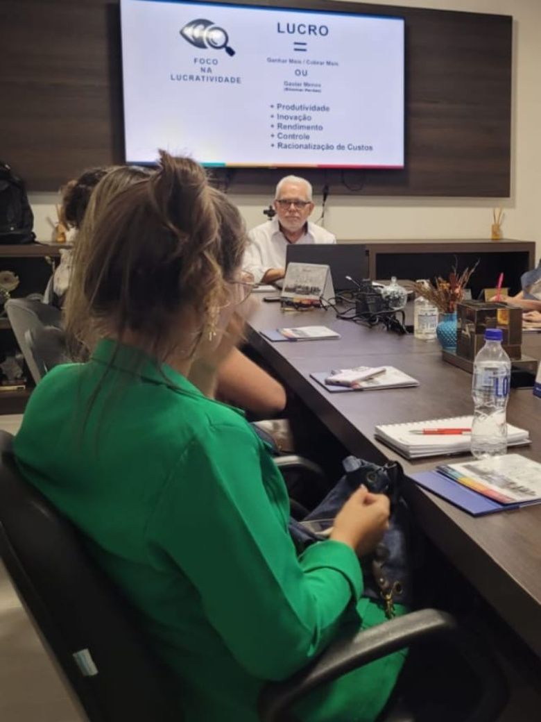 Uma mulher de camisa verde sentada em uma mesa de conferência