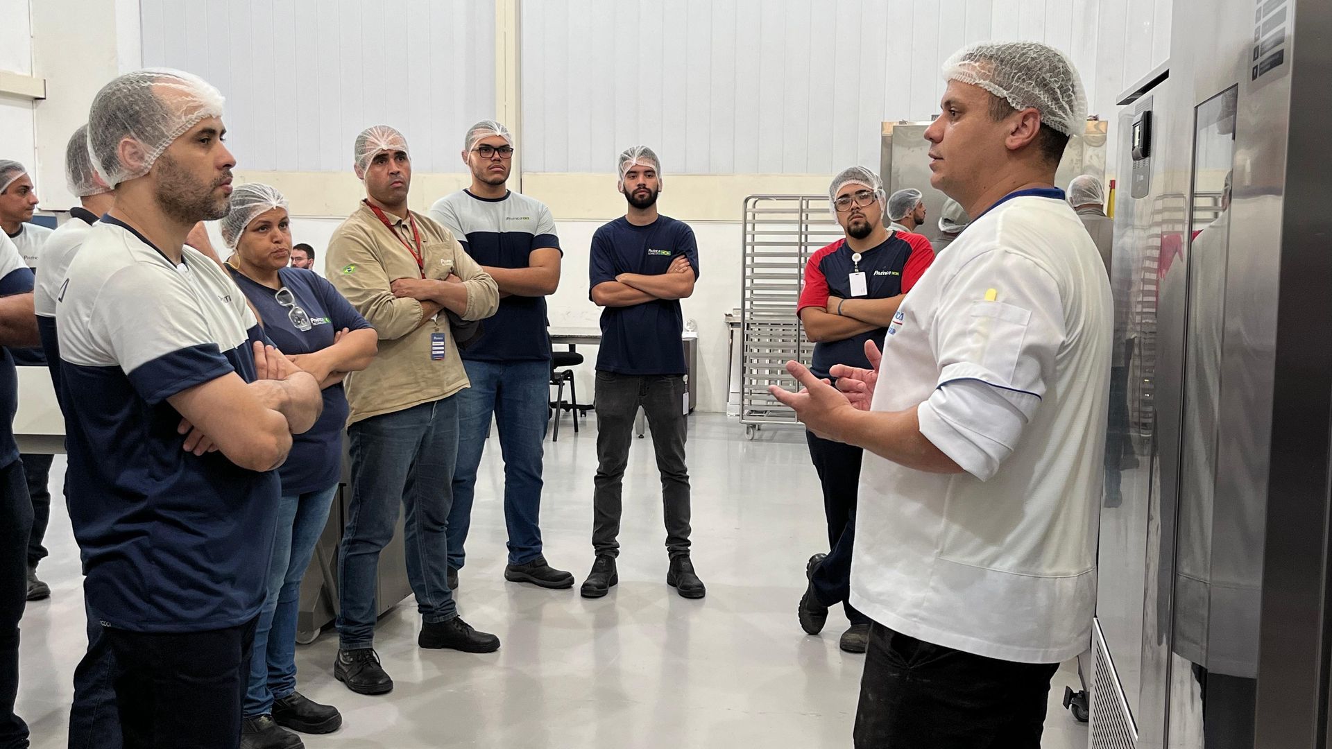 Um homem está conversando com um grupo de pessoas em uma fábrica.