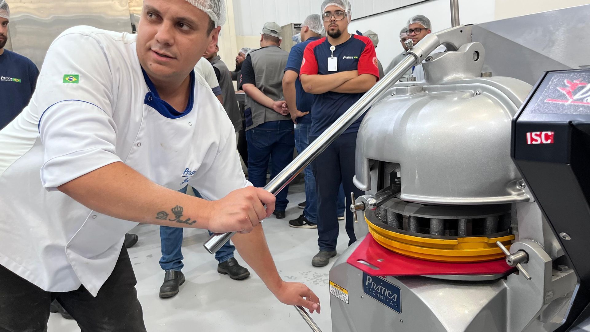 Um homem está parado em frente a uma máquina em uma padaria.
