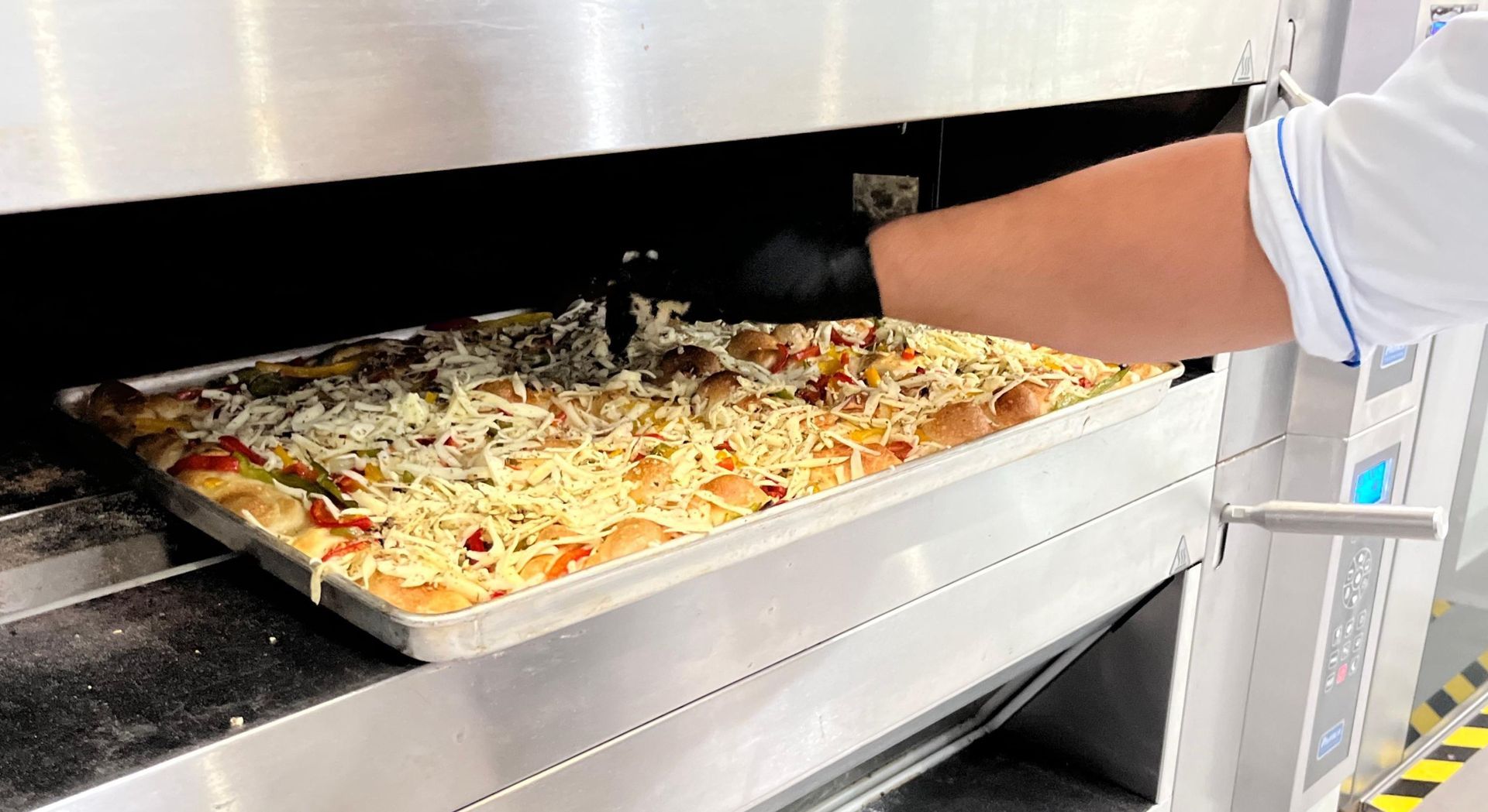 Uma pessoa está tirando uma pizza do forno.