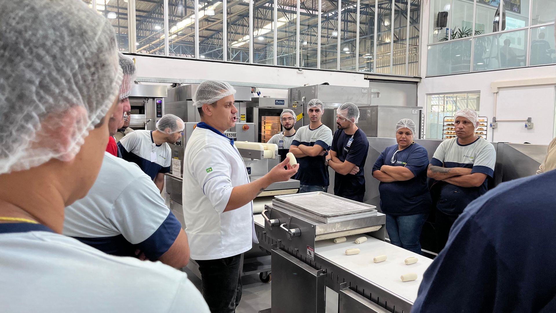 Um homem está fazendo uma apresentação para um grupo de pessoas em uma padaria.