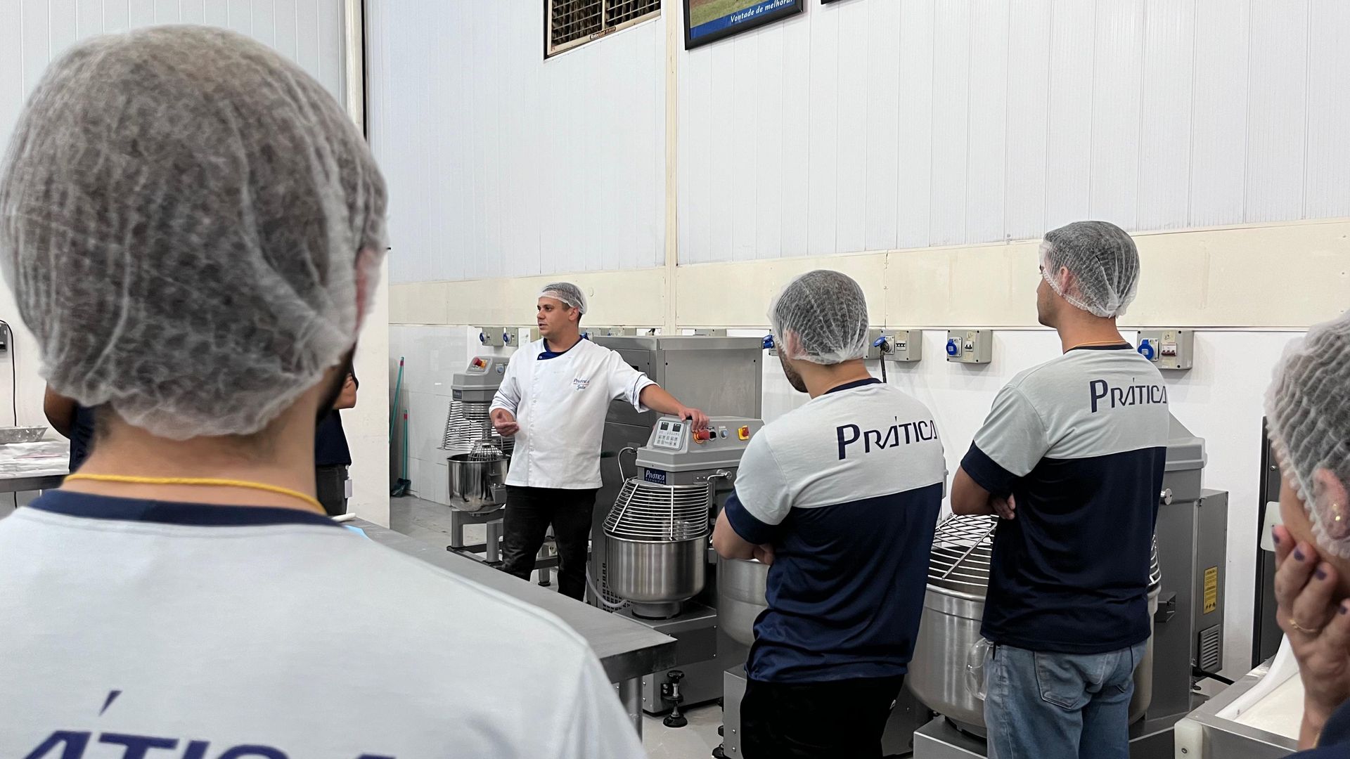 Um grupo de pessoas usando redes de cabelo estão em uma cozinha.