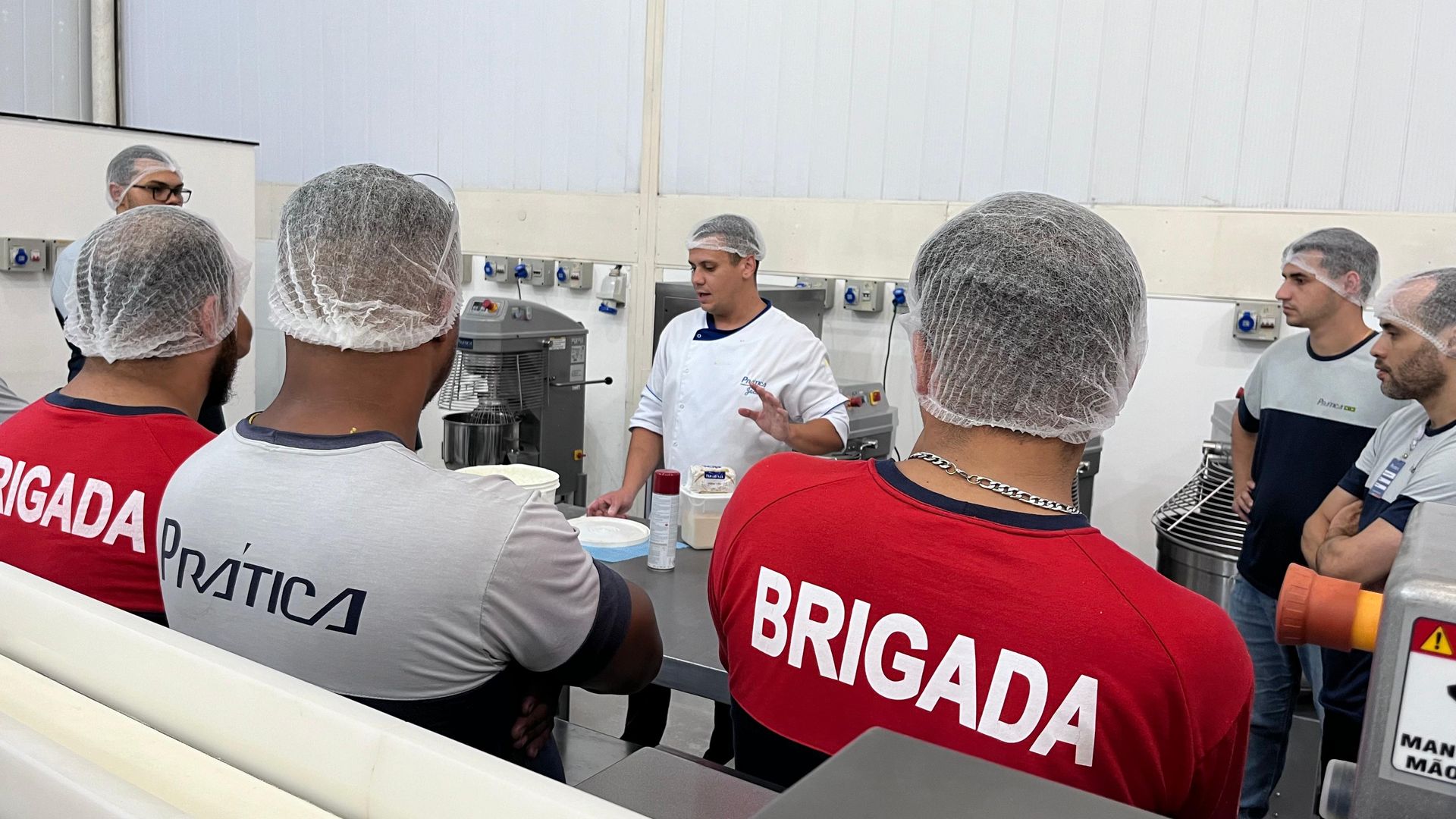 Um grupo de homens vestindo camisas vermelhas com a palavra brigada nas costas estão em uma sala.