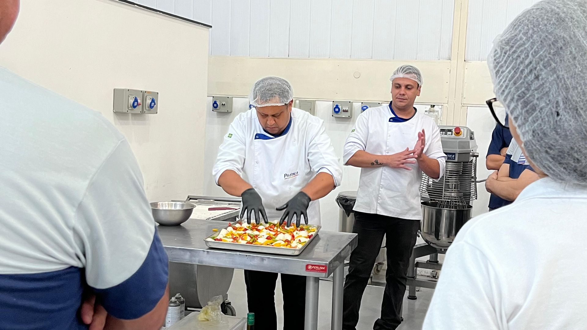 Um grupo de pessoas está observando um chef preparando comida em uma cozinha.