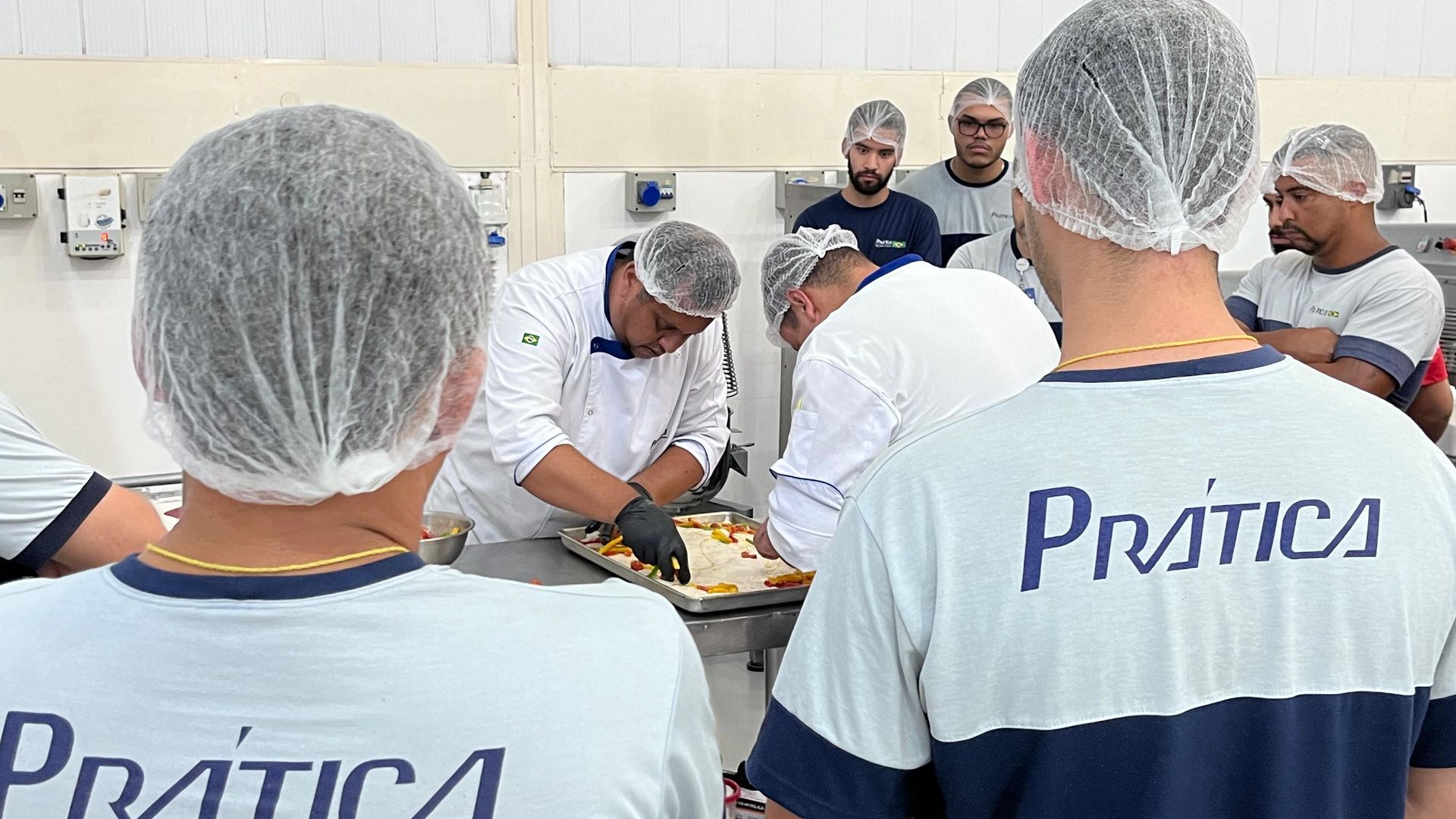 Um grupo de homens usando redes de plástico para cabelo e camisas com a palavra pratica nas costas