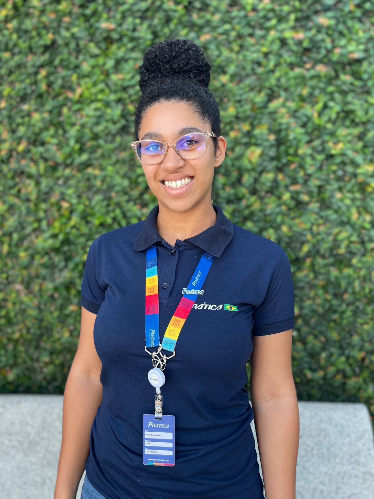 Uma mulher usando óculos e um cordão está sorrindo para a câmera.