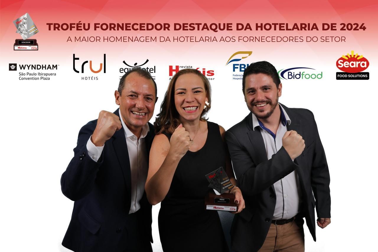 Três pessoas estão posando para uma foto com os punhos no ar.