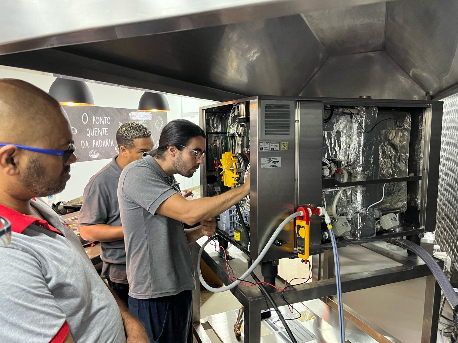 Um grupo de homens está trabalhando em uma máquina em uma cozinha.