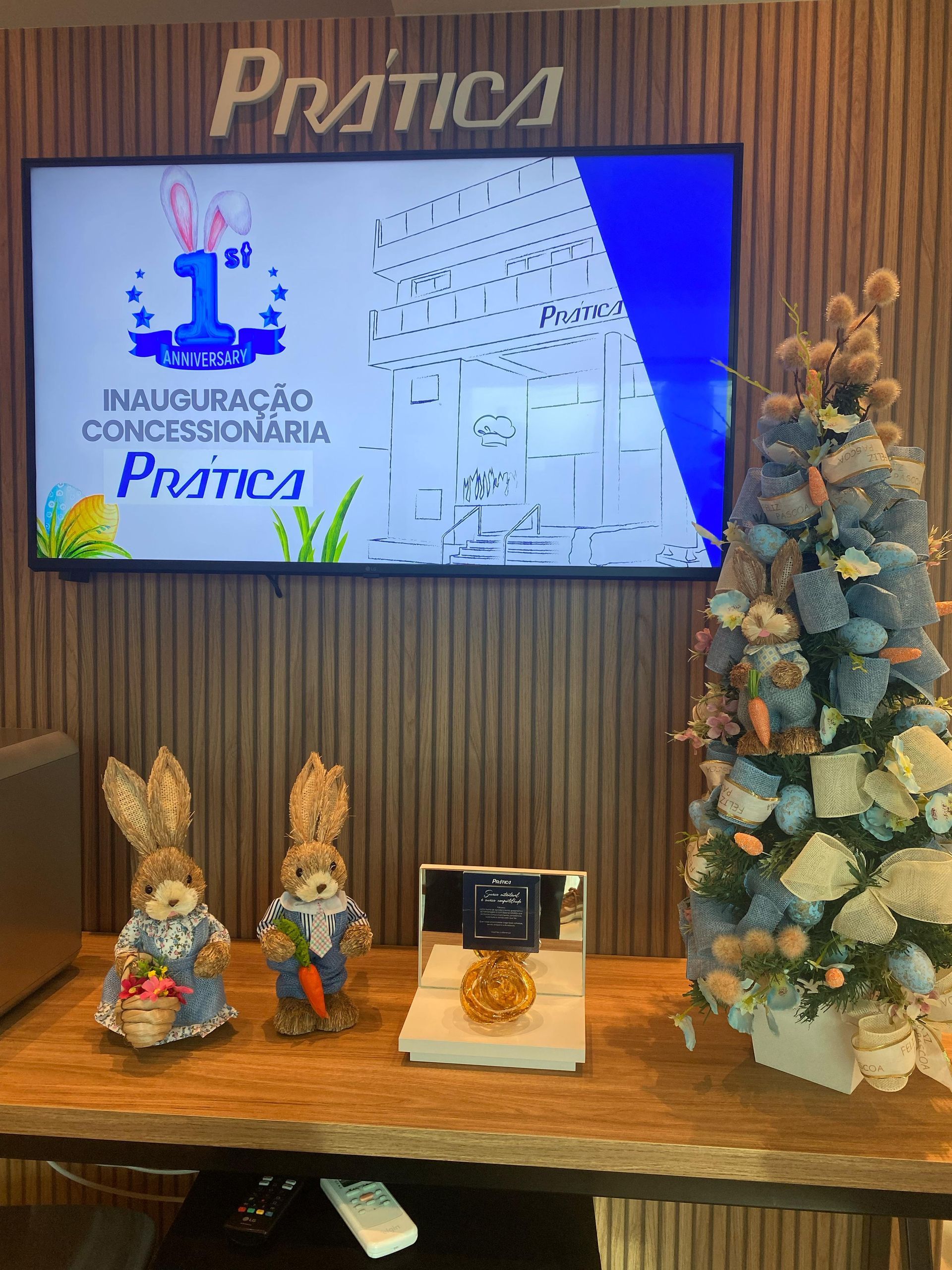 Três coelhos de pelúcia estão sentados em uma mesa em frente a uma TV de tela plana.