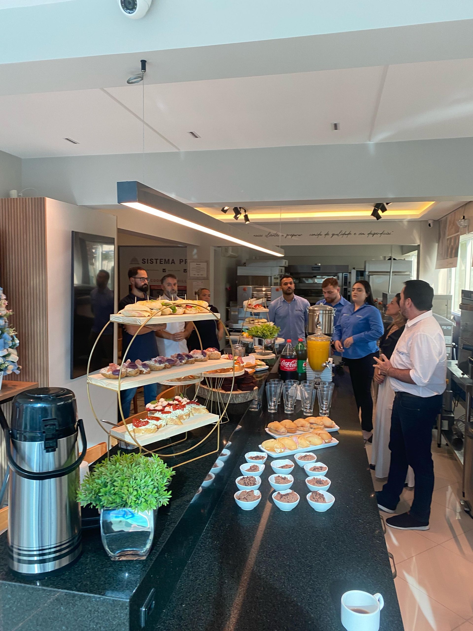 Um grupo de pessoas está em pé ao redor de uma mesa com comida.