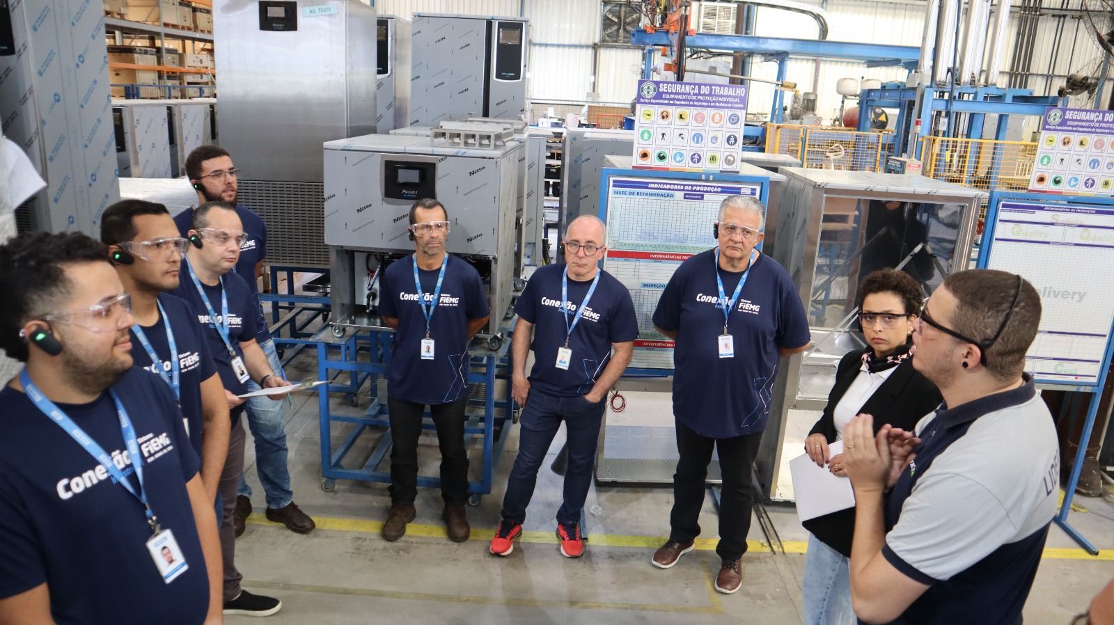 Um grupo de homens está em uma fábrica conversando entre si.
