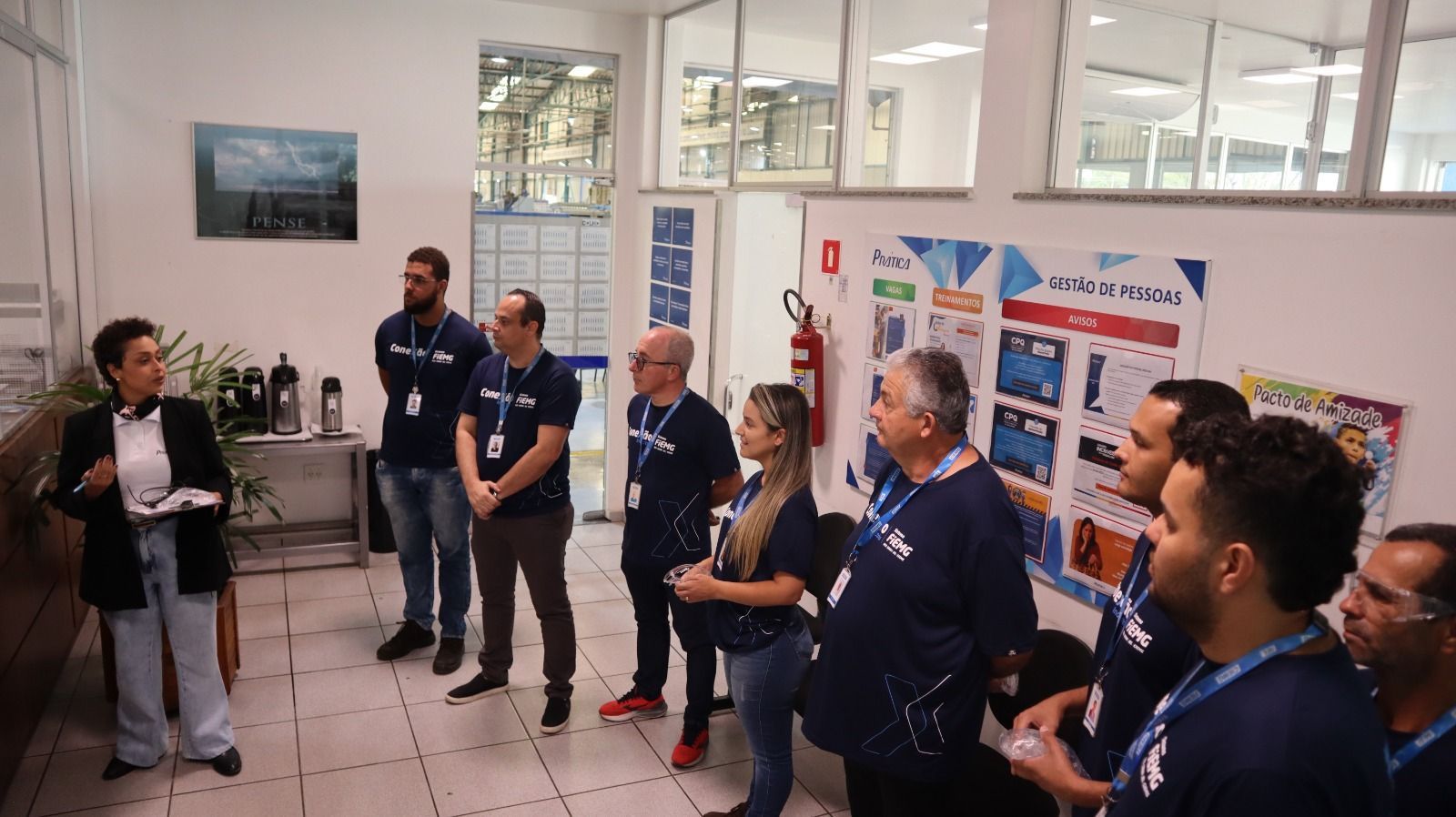 Um grupo de pessoas está em uma sala conversando entre si.