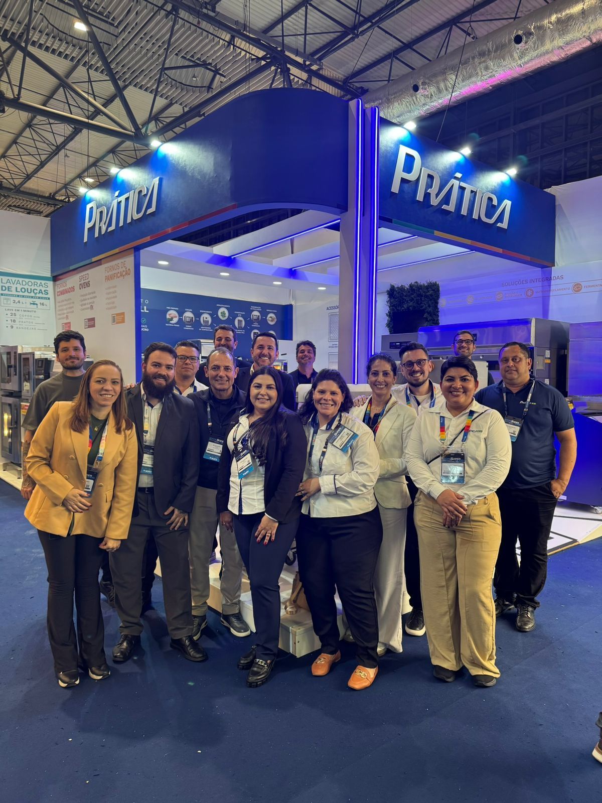 Um grupo de pessoas está posando para uma foto em frente a um estande em uma convenção.