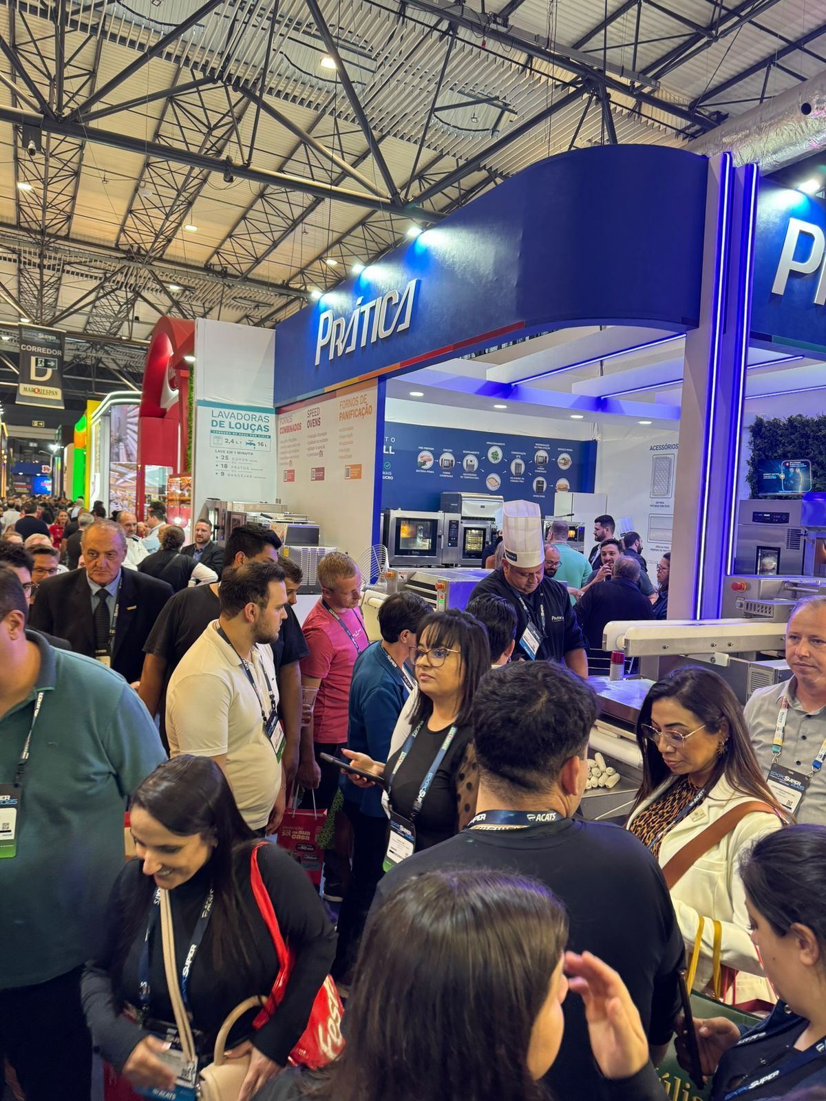 Um grande grupo de pessoas está em frente a um estande em uma convenção.