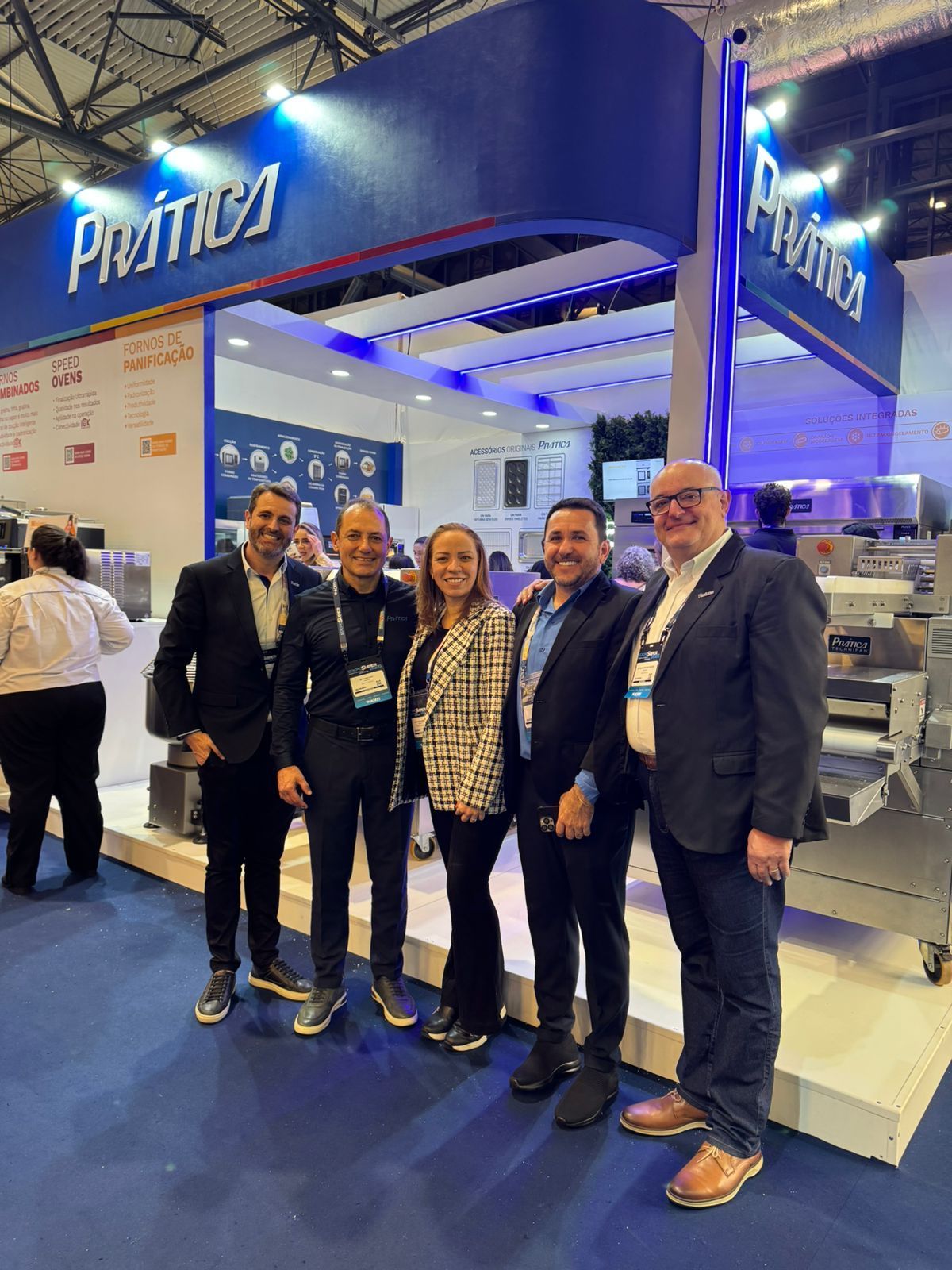 Um grupo de pessoas está em frente a um estande em uma convenção.