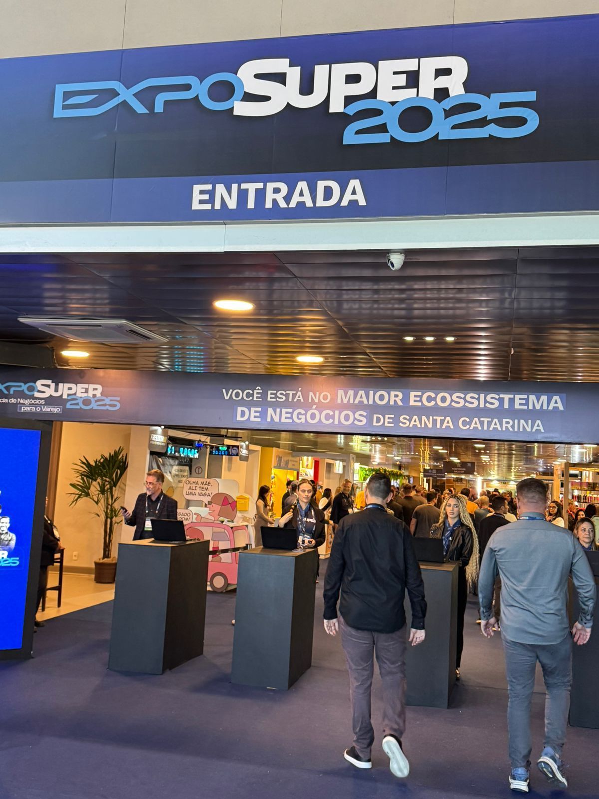 Um grupo de pessoas está caminhando pela entrada da expo super 2025.