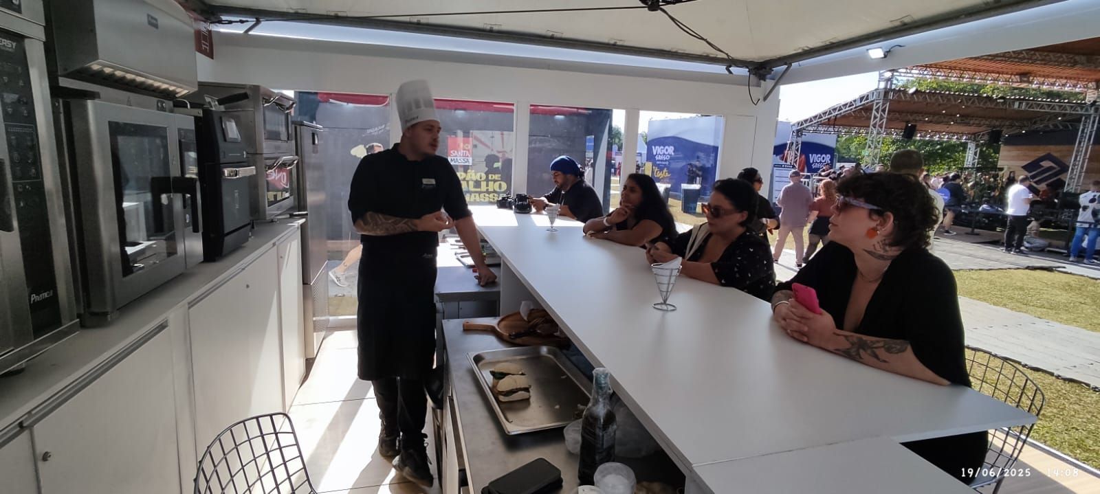 Um grupo de pessoas está sentado em uma longa mesa na cozinha.