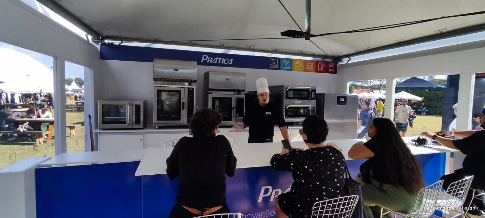 Um grupo de pessoas está sentado em um balcão dentro de uma barraca.