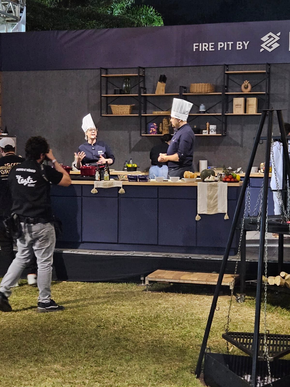 Um homem está tirando uma foto de dois chefs em frente a uma placa que diz fogueira por