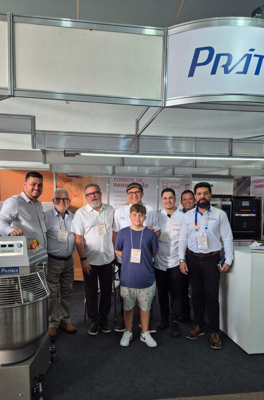 Um grupo de homens está posando para uma foto em frente a uma placa que diz pra