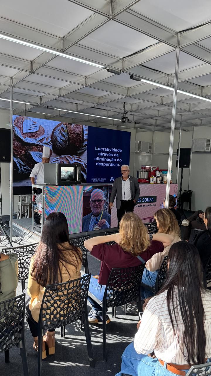 Um grupo de pessoas está sentado em cadeiras assistindo a uma apresentação.