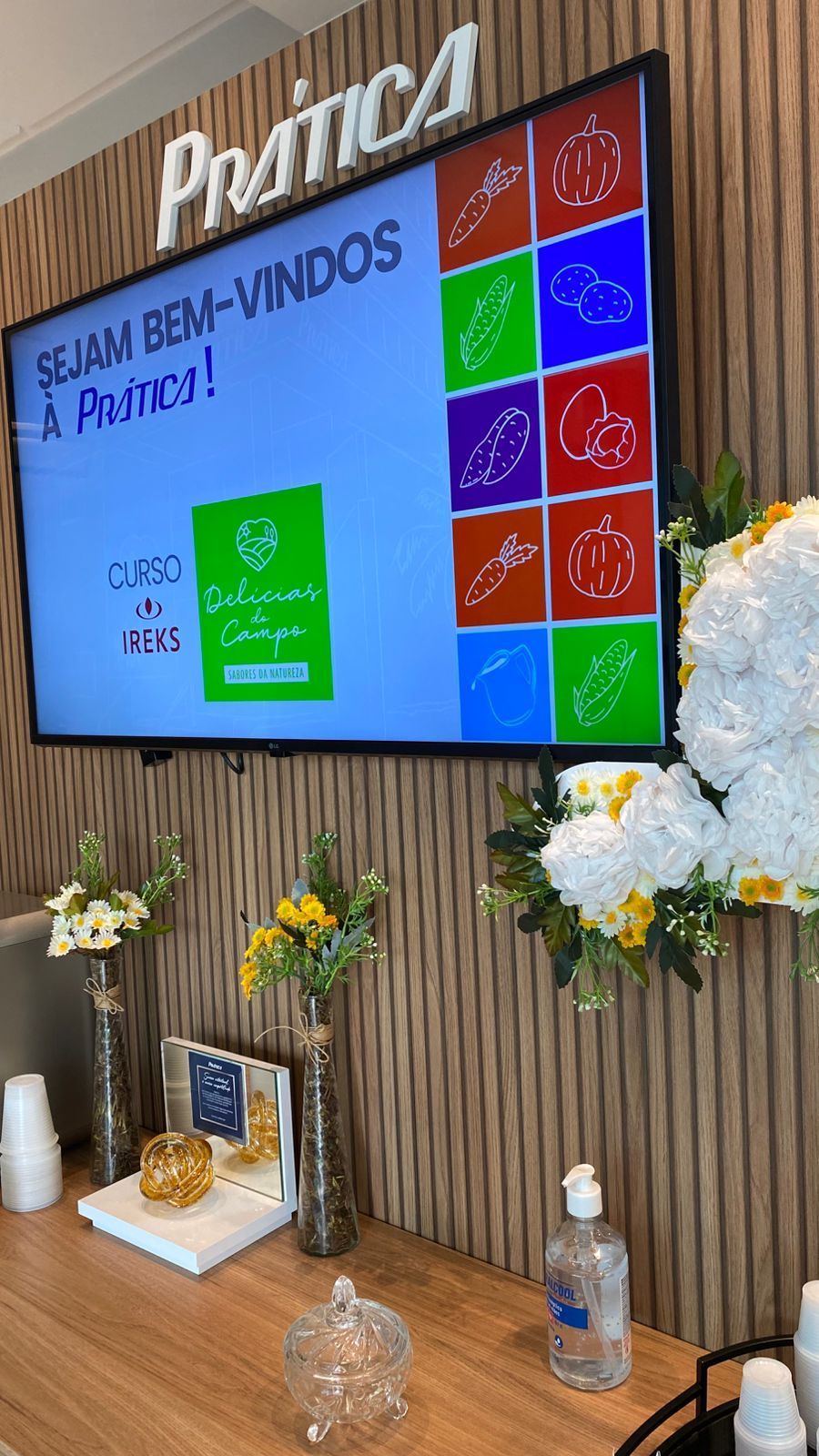 Uma grande TV de tela plana está pendurada na parede acima de uma mesa de madeira.