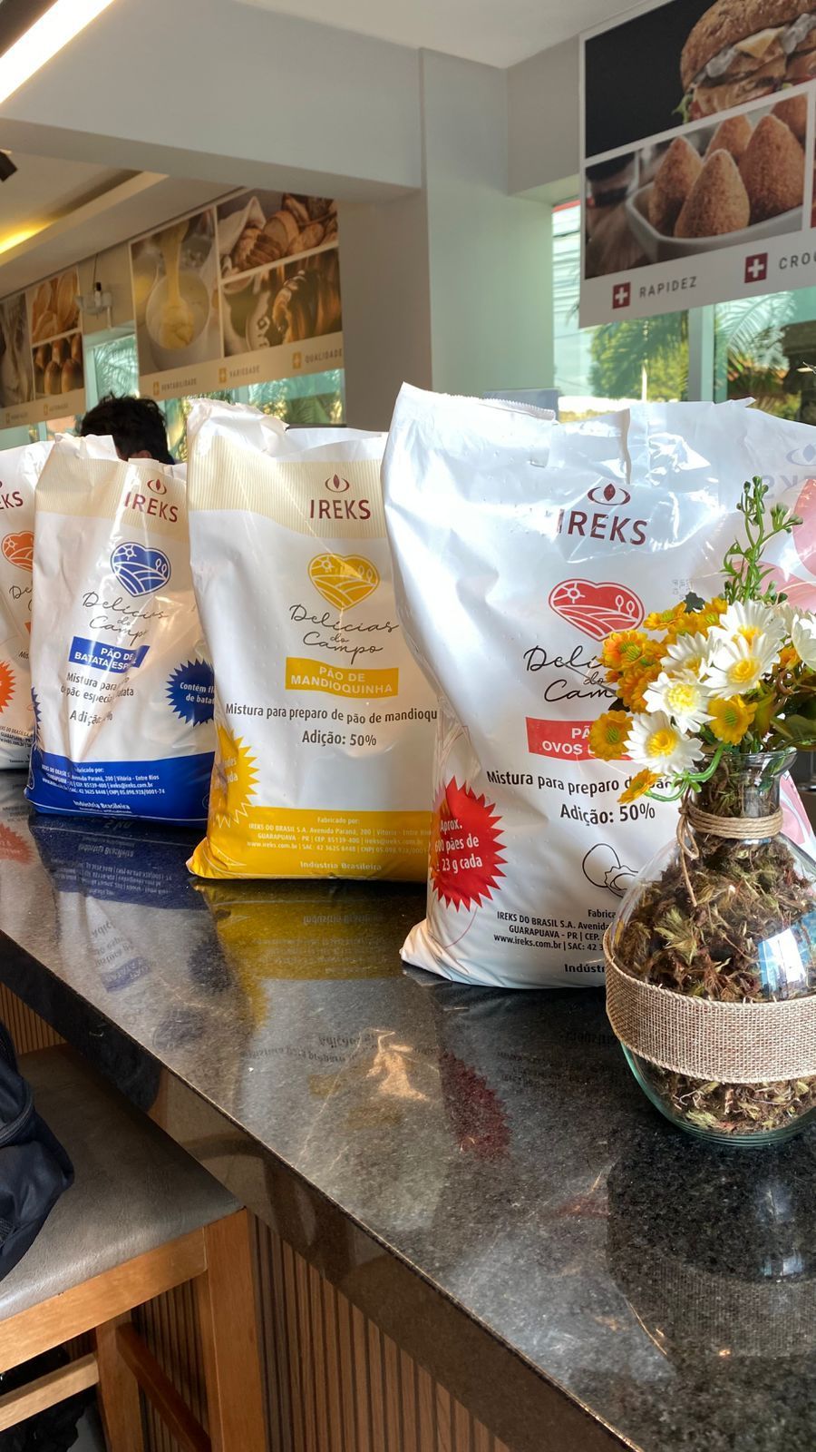 Vários sacos de farinha estão sobre o balcão de uma padaria.