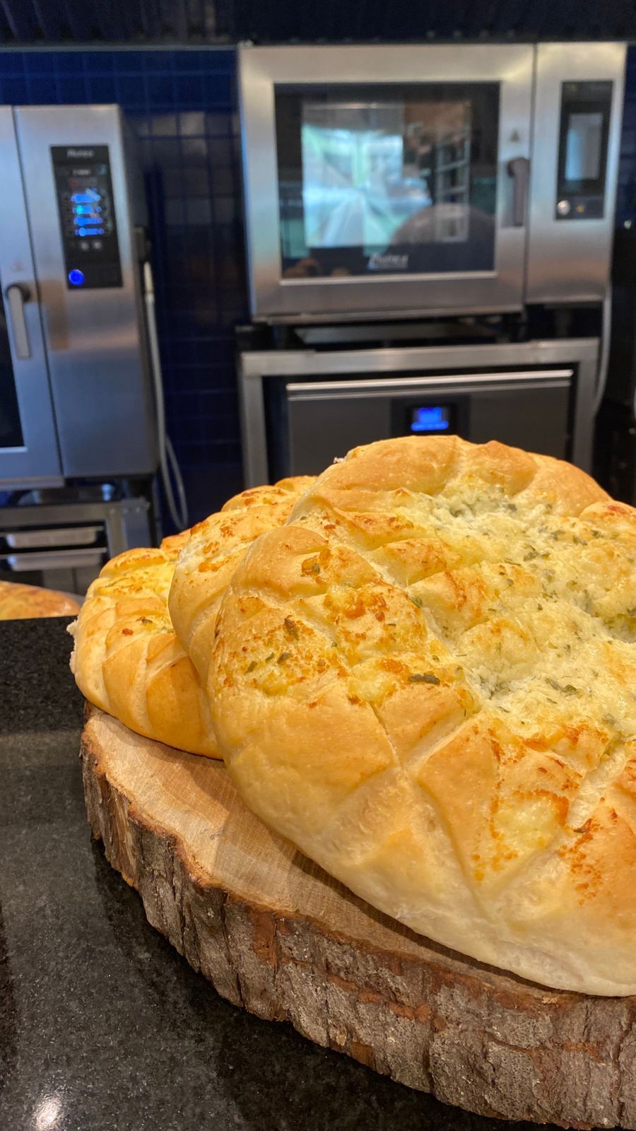 Um pão de alho está sobre uma tábua de corte de madeira.
