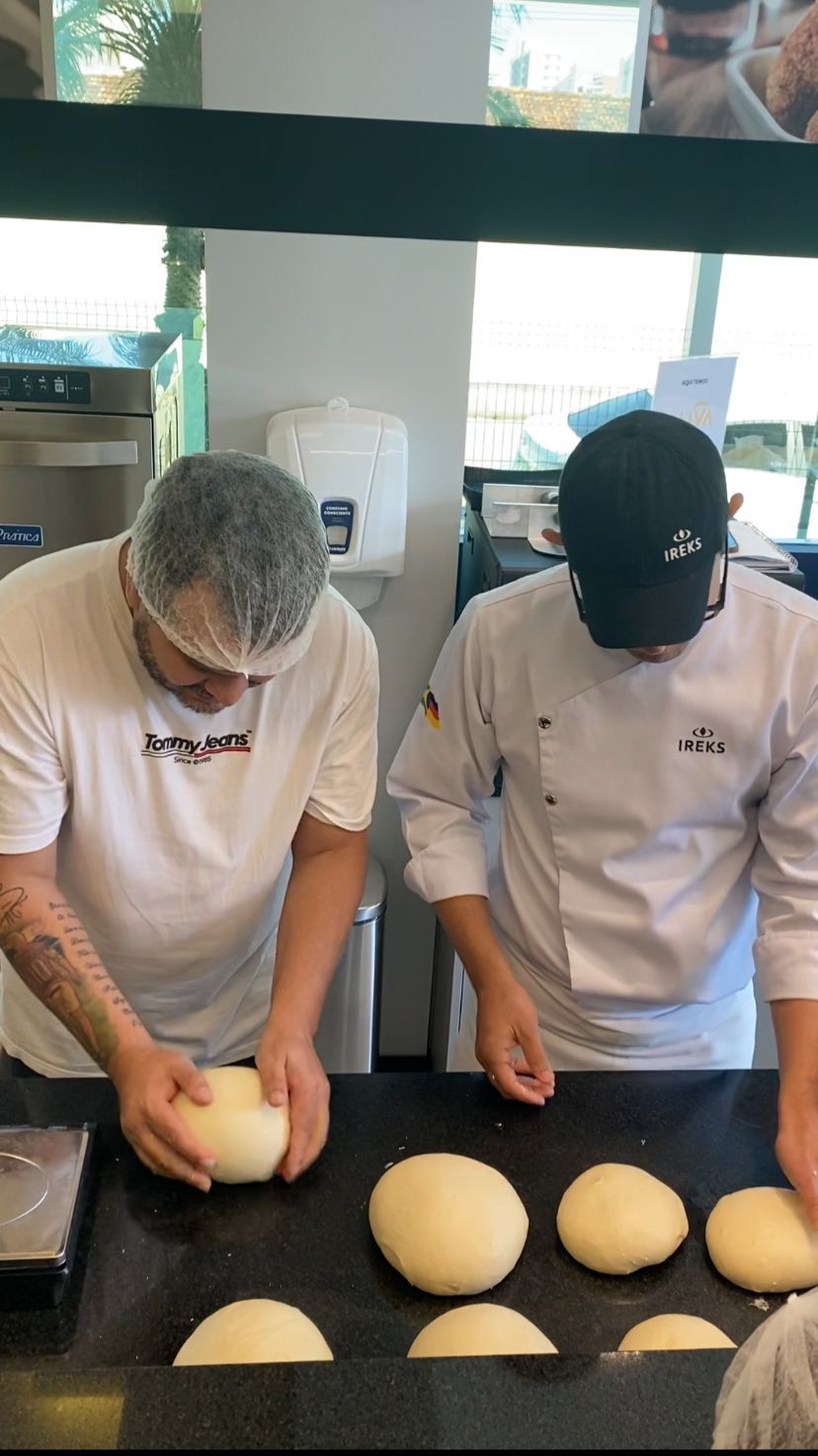 Dois homens estão amassando massa em uma mesa de cozinha.