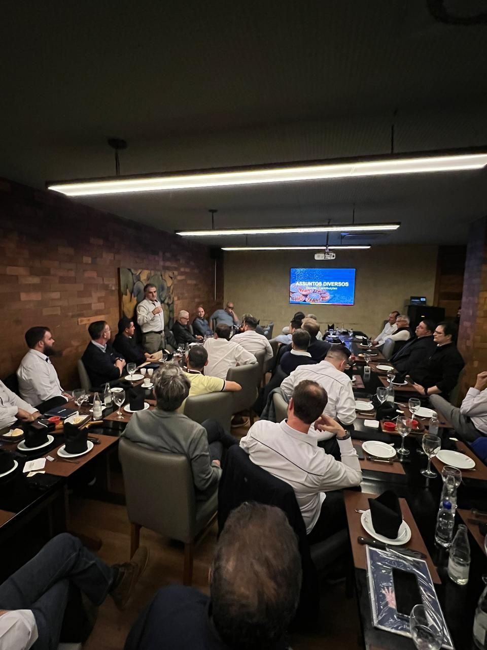 Um grupo de pessoas está sentado em mesas em uma sala.