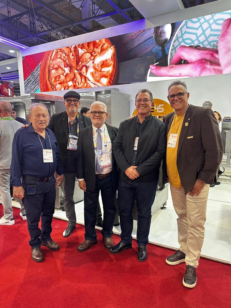 Um grupo de pessoas está em frente a uma exposição de pães.