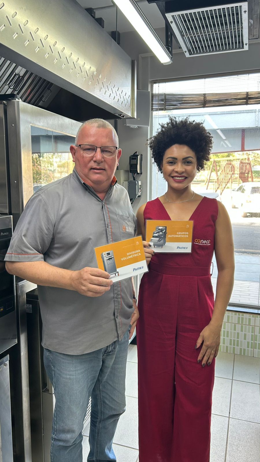 Homem e mulher em restaurante segurando folhetos, sorrindo.