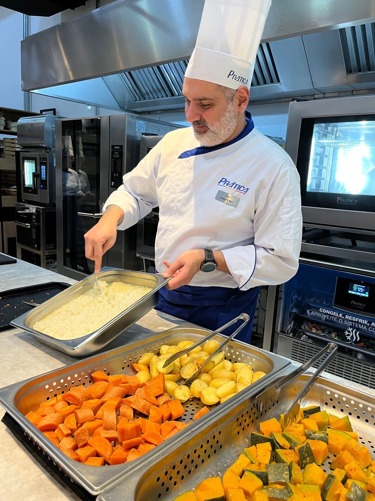 Chef de uniforme branco mexendo comida na cozinha, preparando pratos.