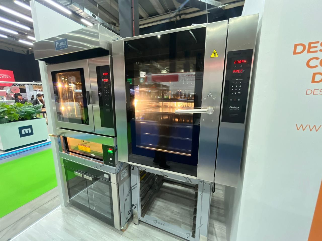 Fornos comerciais em exposição em uma feira. Aço inoxidável, com controles digitais e portas de vidro.