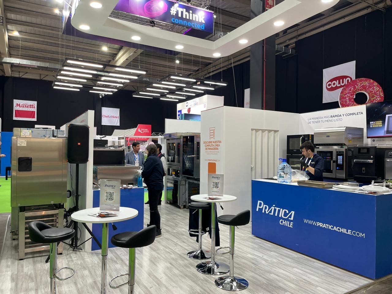 Estande de feira com equipamentos de cozinha comercial, participantes e marca.