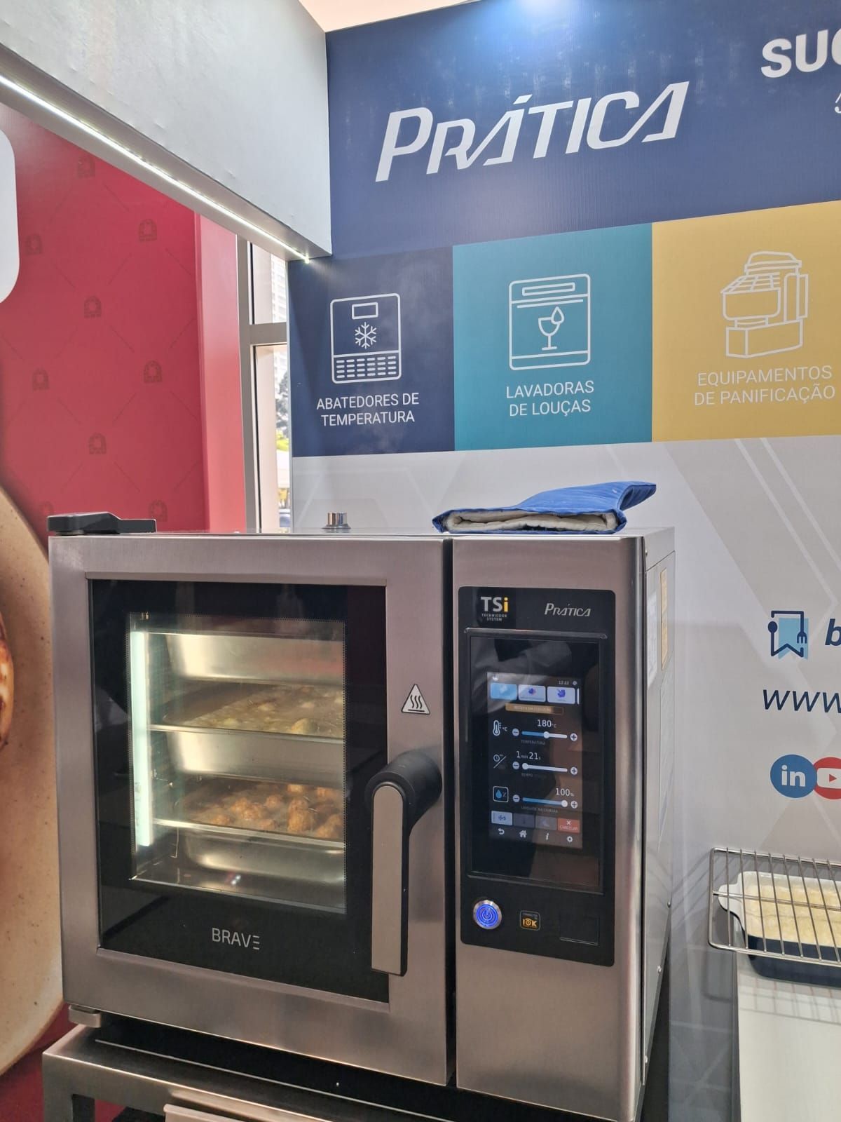 Forno de aço inoxidável, porta aberta, comida dentro, em uma feira gastronômica. Placa com a inscrição