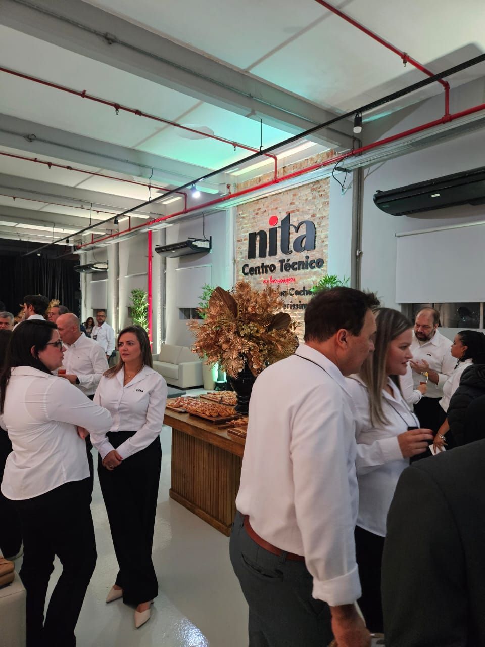 Pessoas em um evento em uma sala com placa