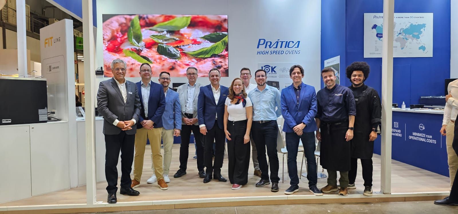 Um grupo de pessoas posando juntas dentro de um estande em uma feira comercial.
