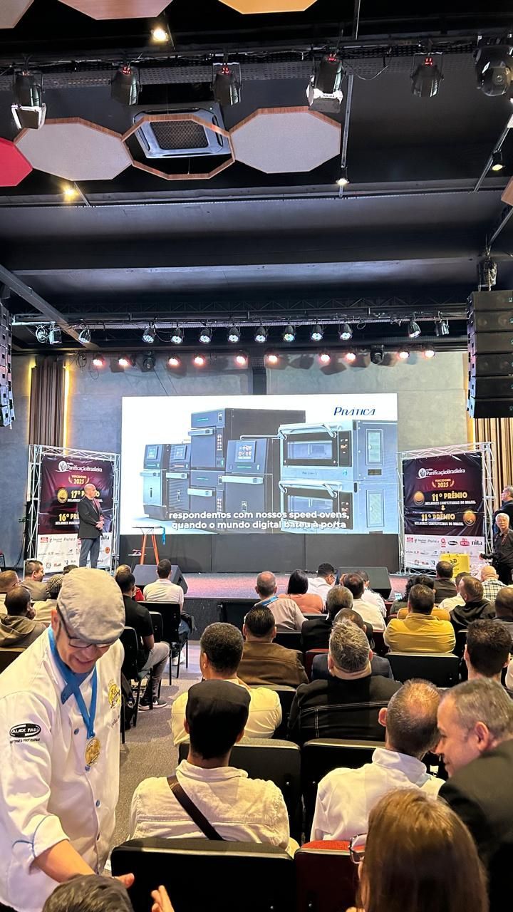 Um chef em um evento culinário, apresentando-se no palco para uma plateia.