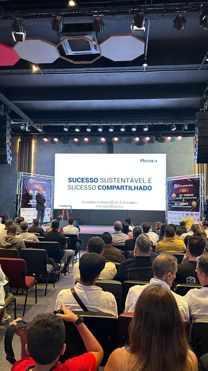 Audience watches speaker at a conference on a large screen with text