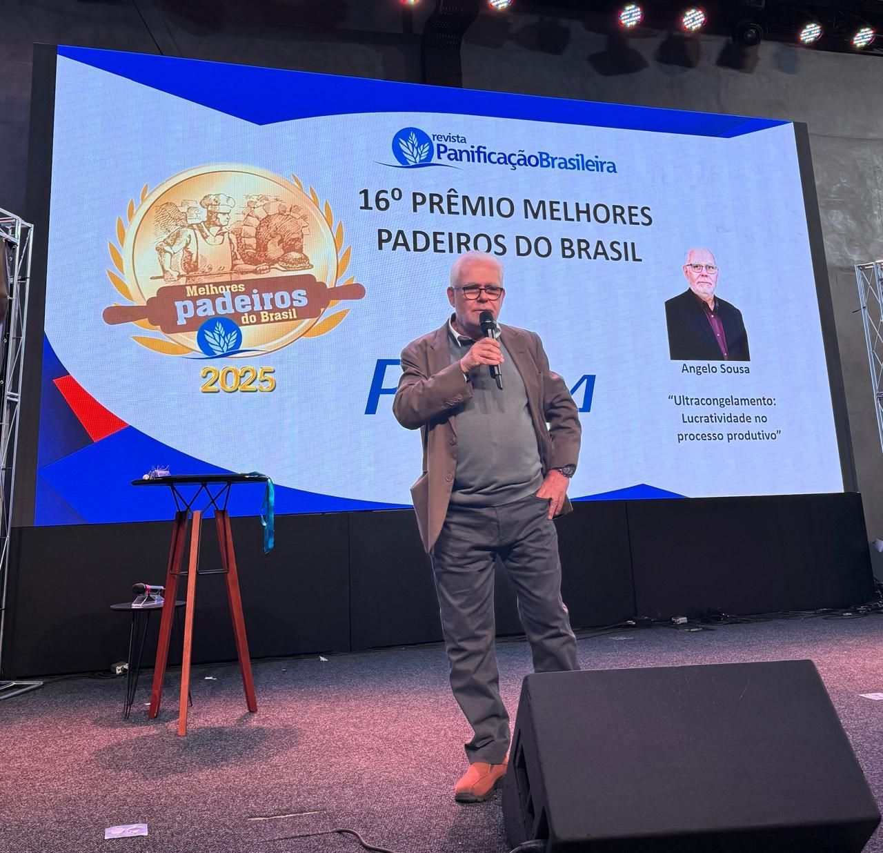 Man speaking at awards event; banner says