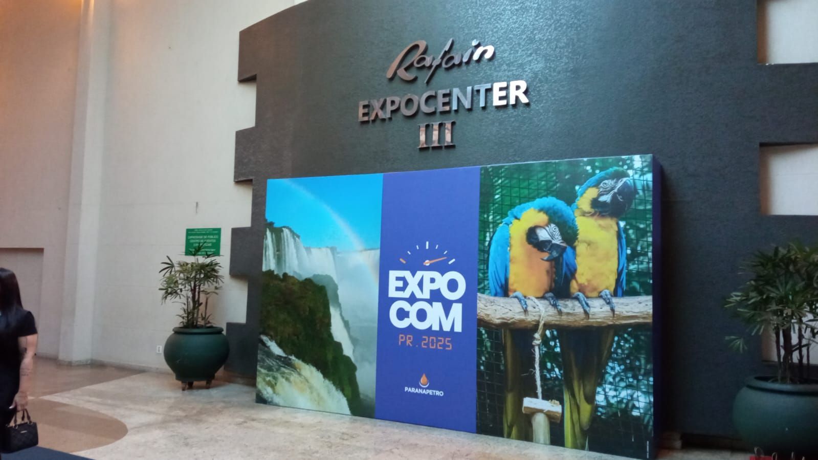 Entrada para o evento EXPOCOM em um centro, com placa, exibição colorida e papagaios.
