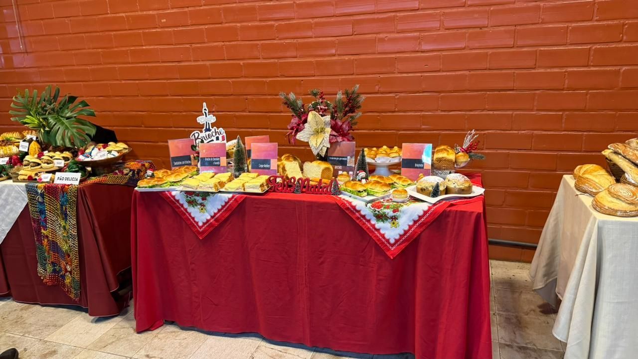 Mesas de bufê repletas de comida, encostadas em uma parede de tijolos vermelhos.