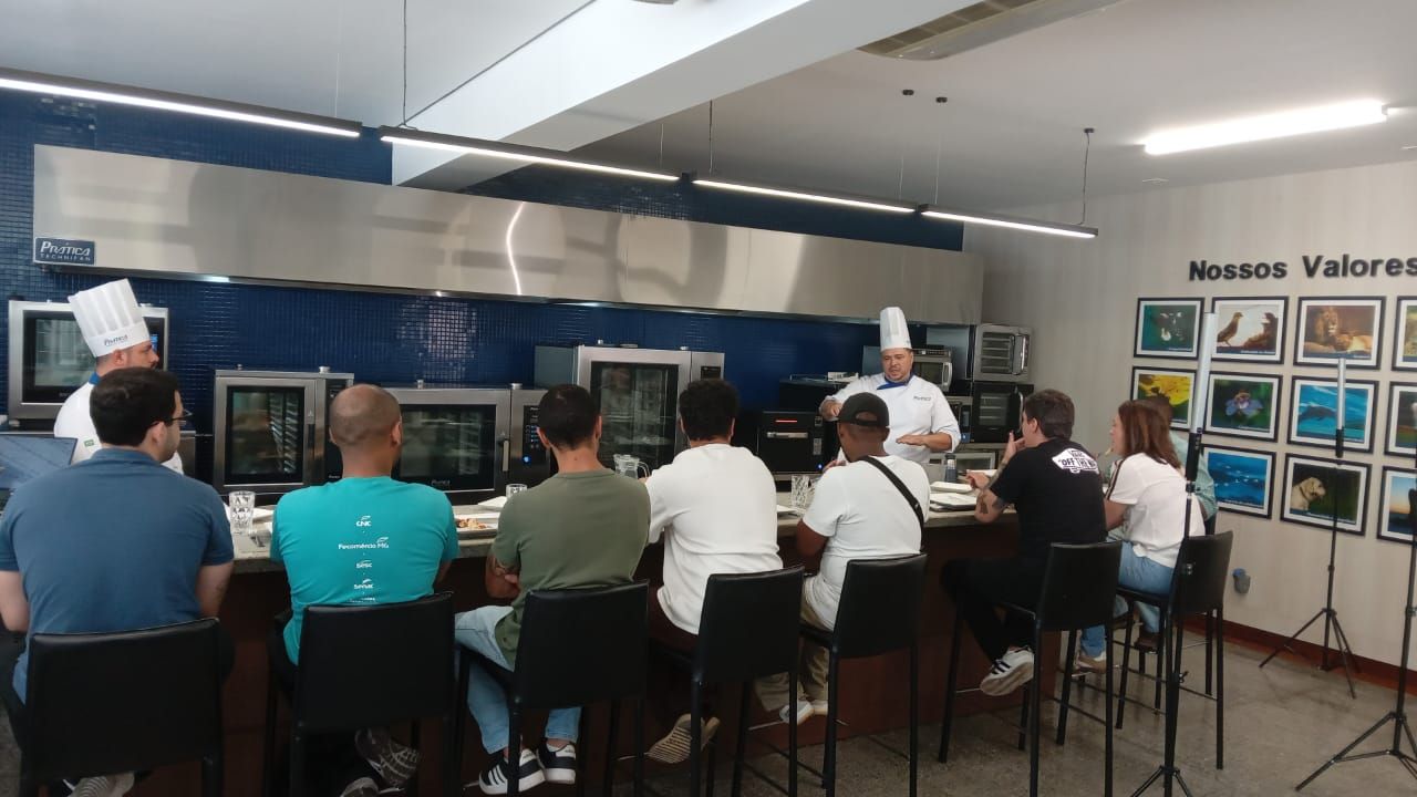 O chef demonstra uma receita para um grupo de pessoas em um balcão. Ambiente de cozinha.