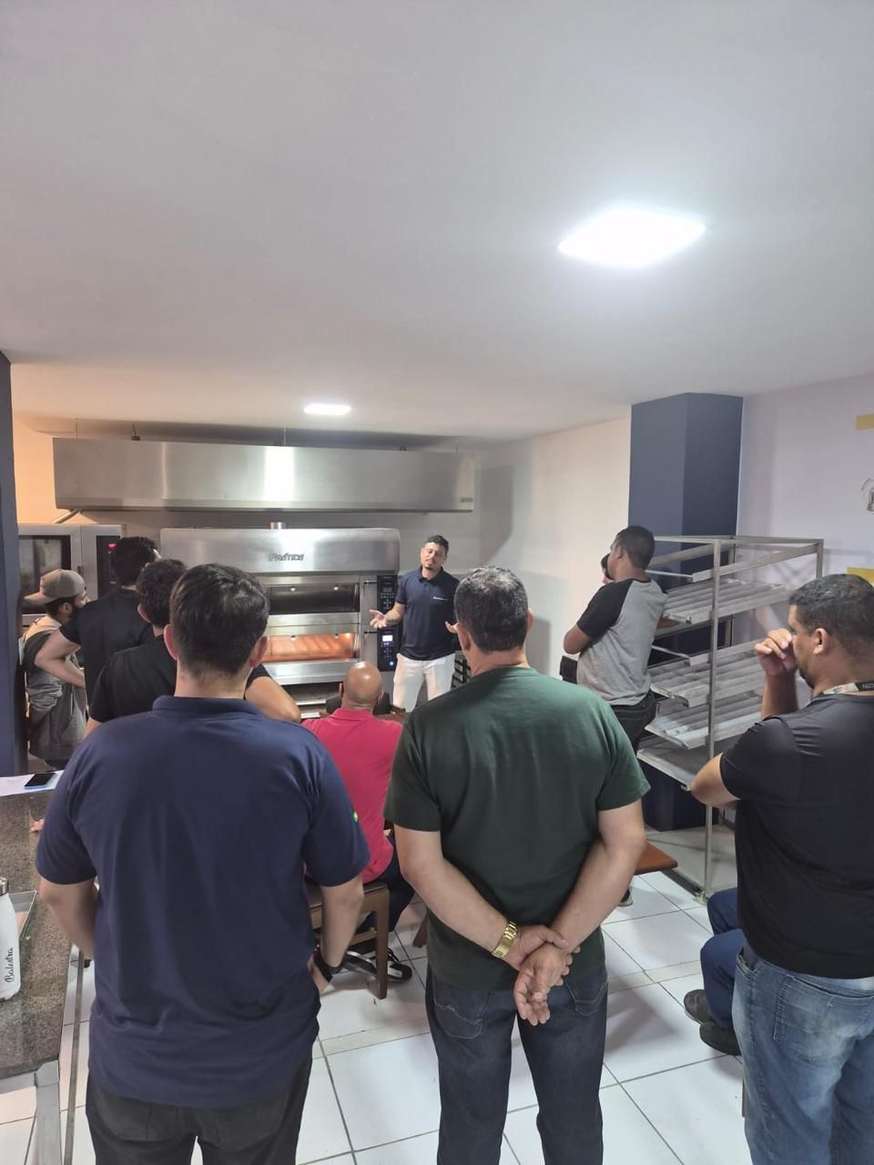 Um grupo de pessoas observa um homem em uma cozinha profissional