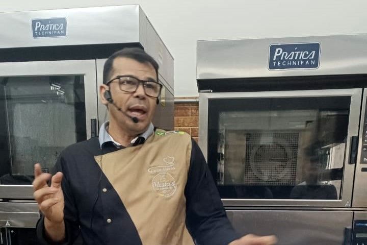 Um homem usando óculos e fone de ouvido está parado em frente a dois fornos.