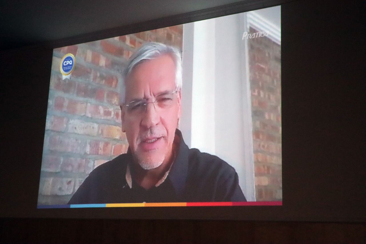 Um homem de óculos e barba está na tela da televisão.