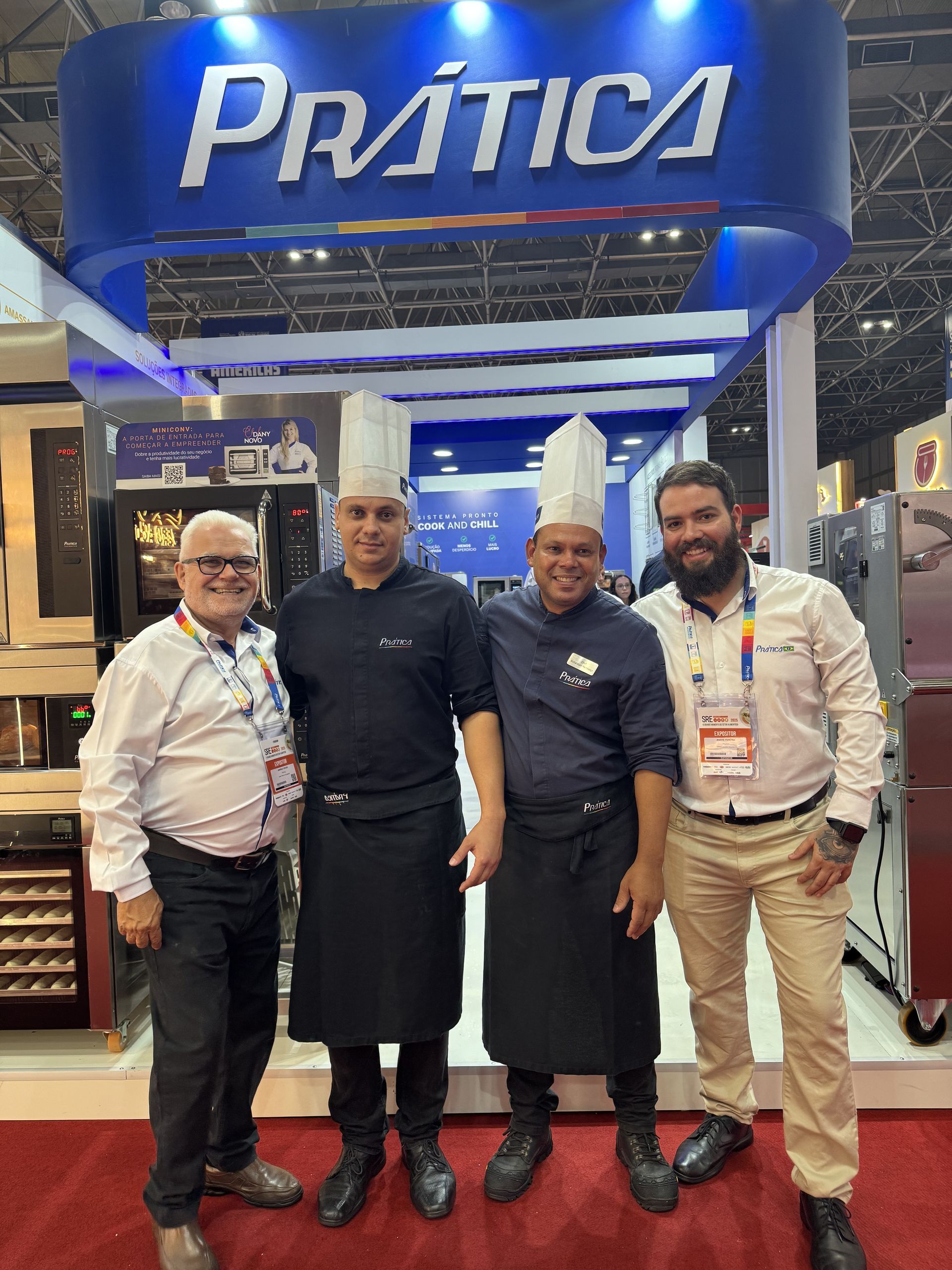 Quatro homens estão posando para uma foto em frente a uma placa de prática